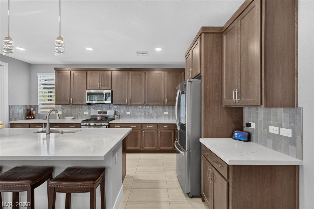 6849 Desert Finch Street, North Las Vegas, NV 89084 Gleaming stone countertops and warm wood cabinetry define this modern open kitchen space.