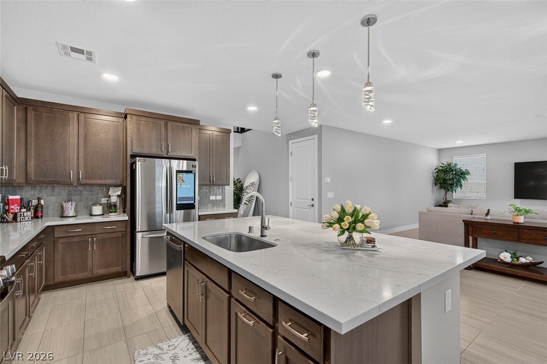 6849 Desert Finch Street, North Las Vegas, NV 89084 Rich wood cabinetry contrasts beautifully with sleek stone countertops in this open kitchen layout.