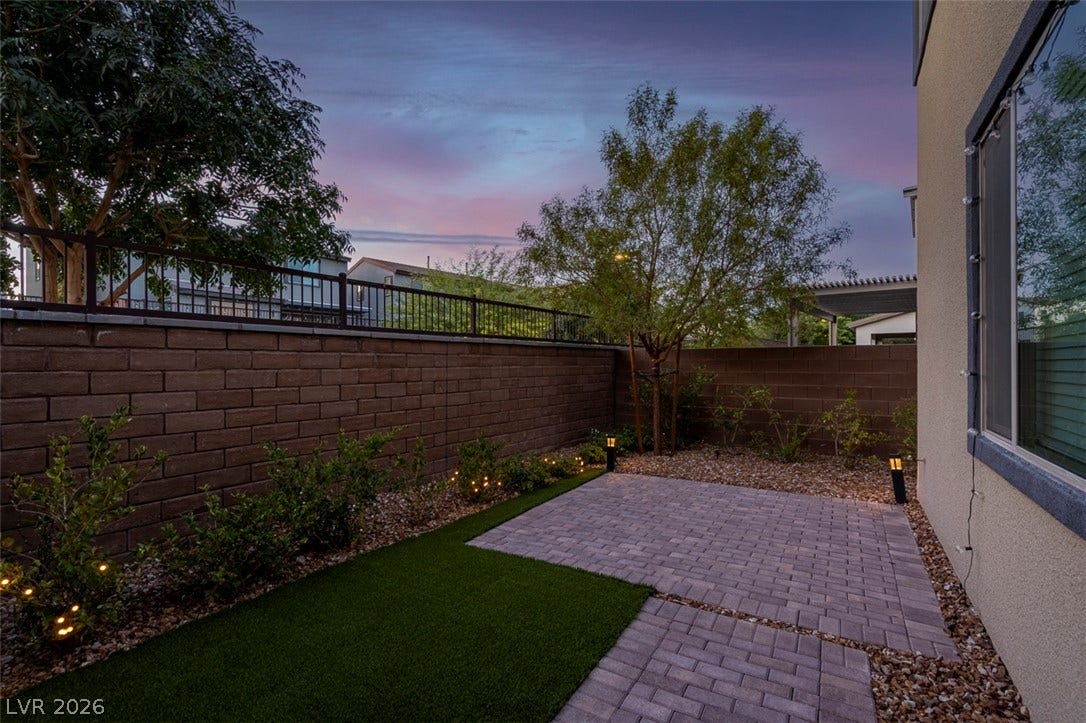 6849 Desert Finch Street, North Las Vegas, NV 89084 An inviting backyard patio features neat brick pavers, manicured greenery, and secure masonry fencing.
