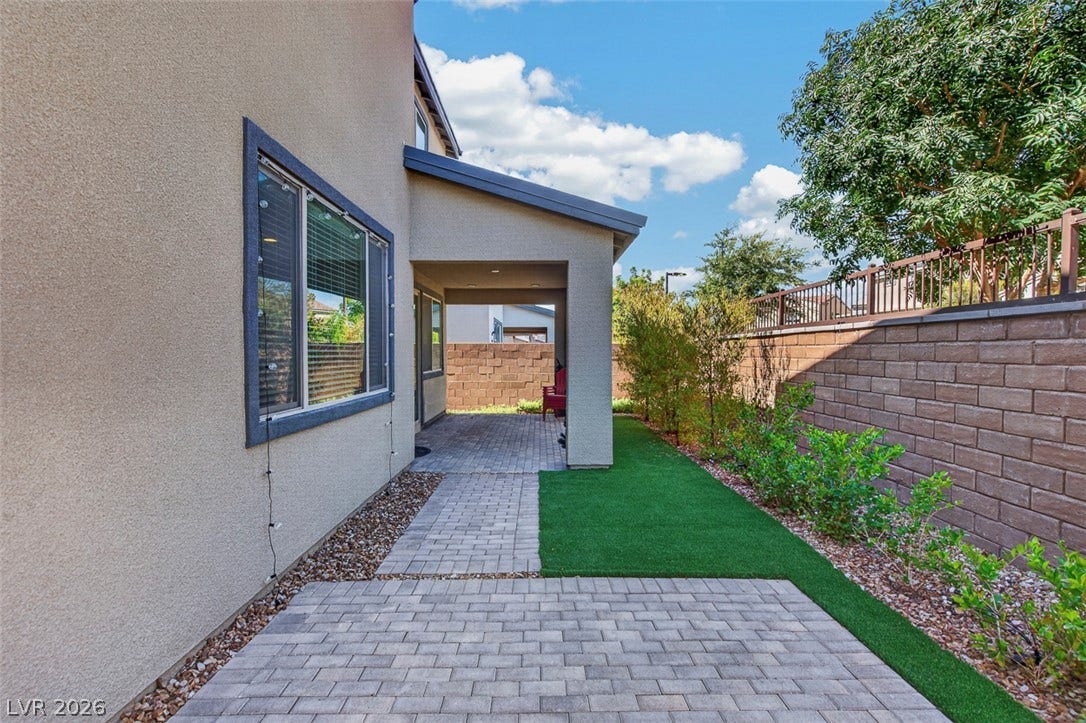6849 Desert Finch Street, North Las Vegas, NV 89084 A paved walkway winds along the stucco exterior toward a covered patio area.