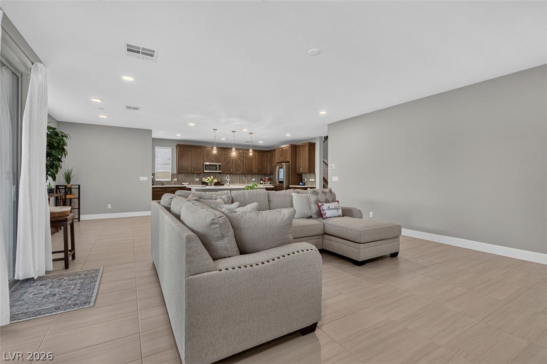 6849 Desert Finch Street, North Las Vegas, NV 89084 Clean tile flooring flows seamlessly through this airy, open-concept living area and kitchen layout.