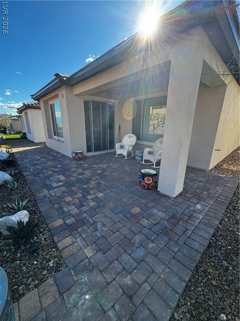162 Palm Fox Court, Henderson, NV 89011 Sunlight illuminates a private paved patio bordered by desert landscaping and stucco walls.