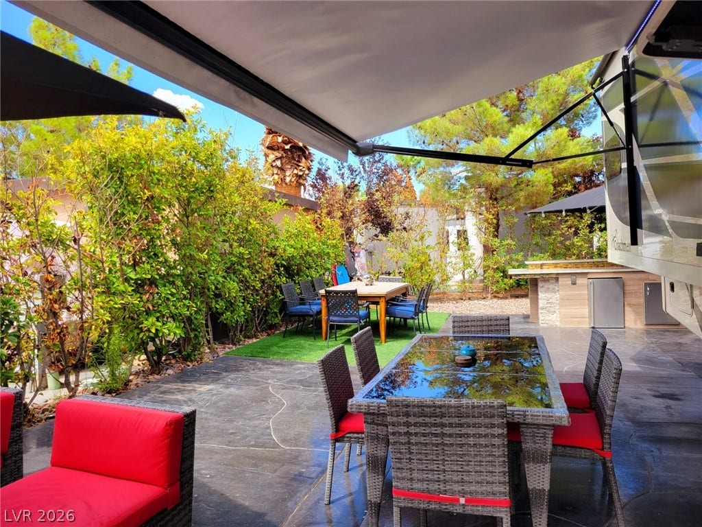 8175 Arville Street, #293, Las Vegas, NV 89139 A spacious stone patio unfolds beneath a retractable awning next to an outdoor kitchen.