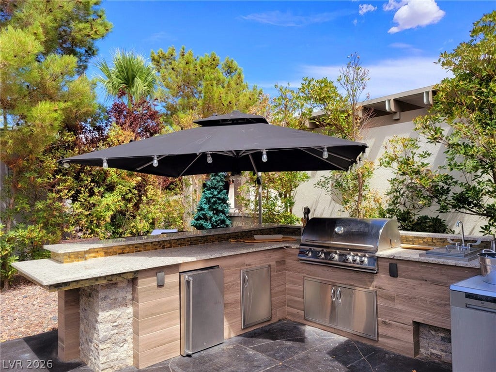 8175 Arville Street, #293, Las Vegas, NV 89139 An integrated outdoor kitchen features stone accents and premium appliances under a sunny sky.