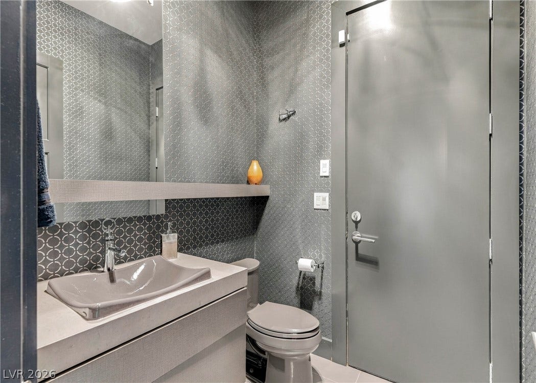 3716 Caesars Circle, Las Vegas, NV 89120 A modern powder room showcases geometric wall coverings and a sleek stone vanity.