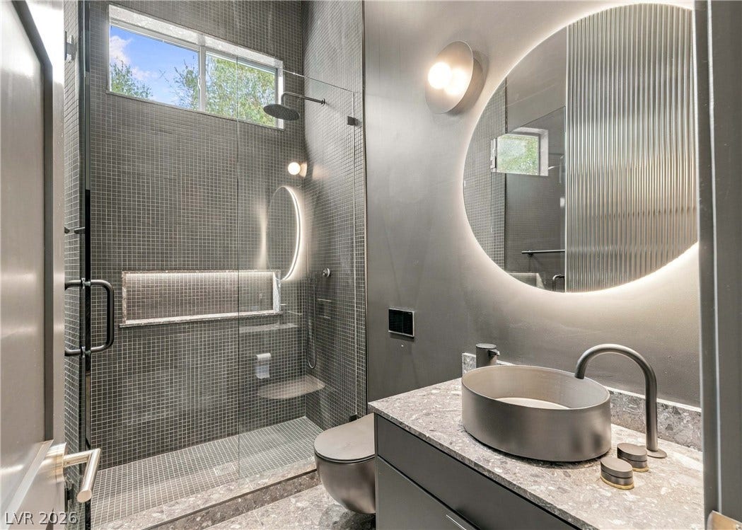 3716 Caesars Circle, Las Vegas, NV 89120 Dramatic mood lighting complements the sleek stone vanity and glass-enclosed walk-in tile shower.