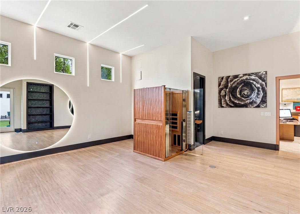 3716 Caesars Circle, Las Vegas, NV 89120 Smooth wood floors and linear light installations elevate this modern home wellness space.