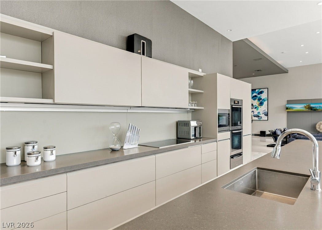3716 Caesars Circle, Las Vegas, NV 89120 Minimalist cabinetry pairs with sleek solid-surface countertops in this contemporary open-concept kitchen.