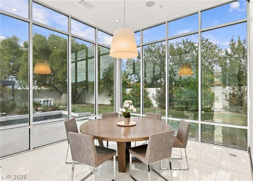3716 Caesars Circle, Las Vegas, NV 89120 Towering floor-to-ceiling windows frame verdant garden views in this modern dining area with polished tile flooring.