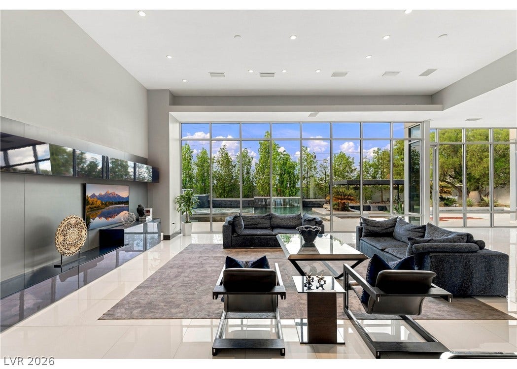 3716 Caesars Circle, Las Vegas, NV 89120 Towering floor-to-ceiling windows look out onto a backyard pool from this modern living area.