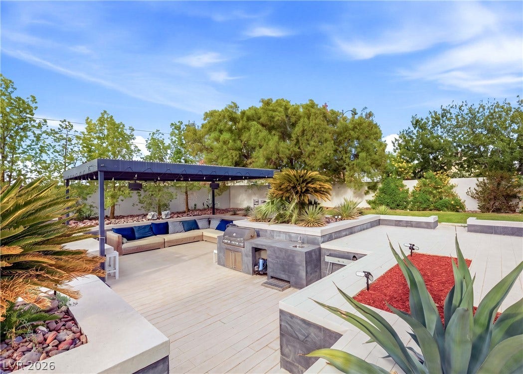 3716 Caesars Circle, Las Vegas, NV 89120 An expansive paved patio includes a built-in outdoor kitchen under clear blue skies.