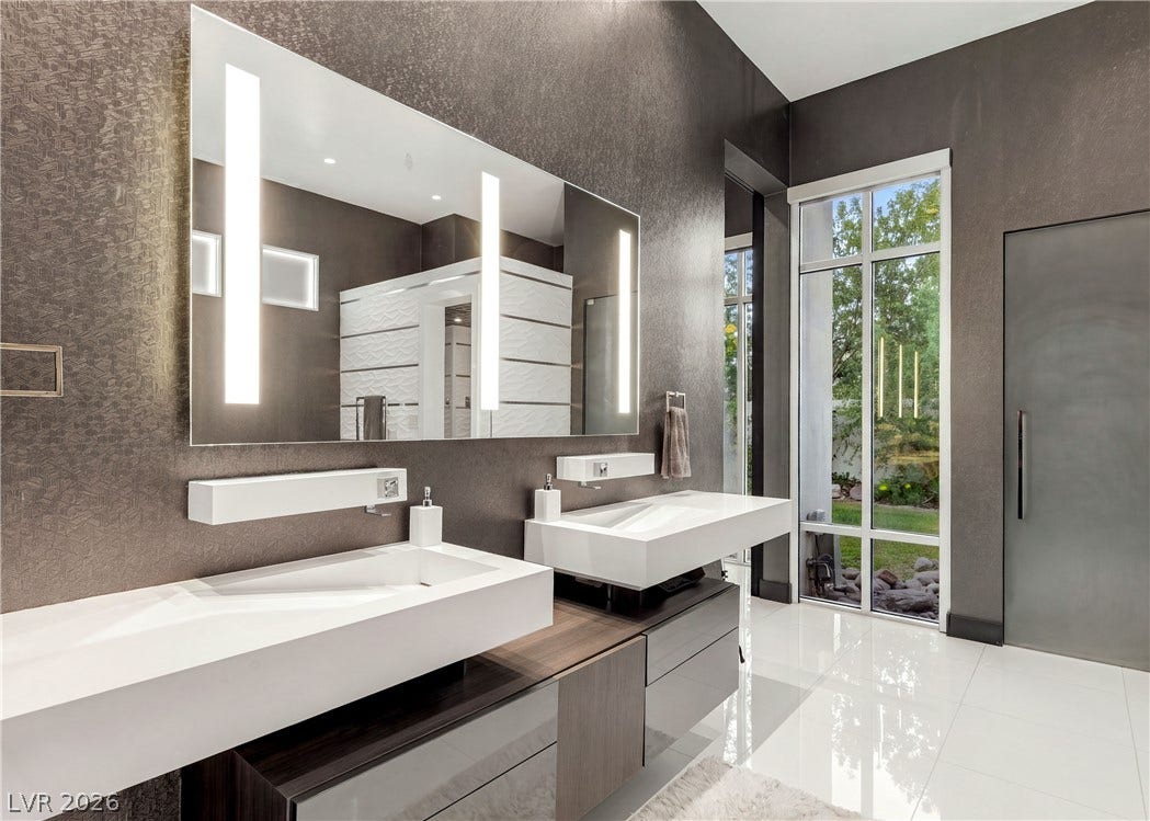 3716 Caesars Circle, Las Vegas, NV 89120 Gleaming tile floors and towering windows elevate this contemporary dual vanity bathroom.