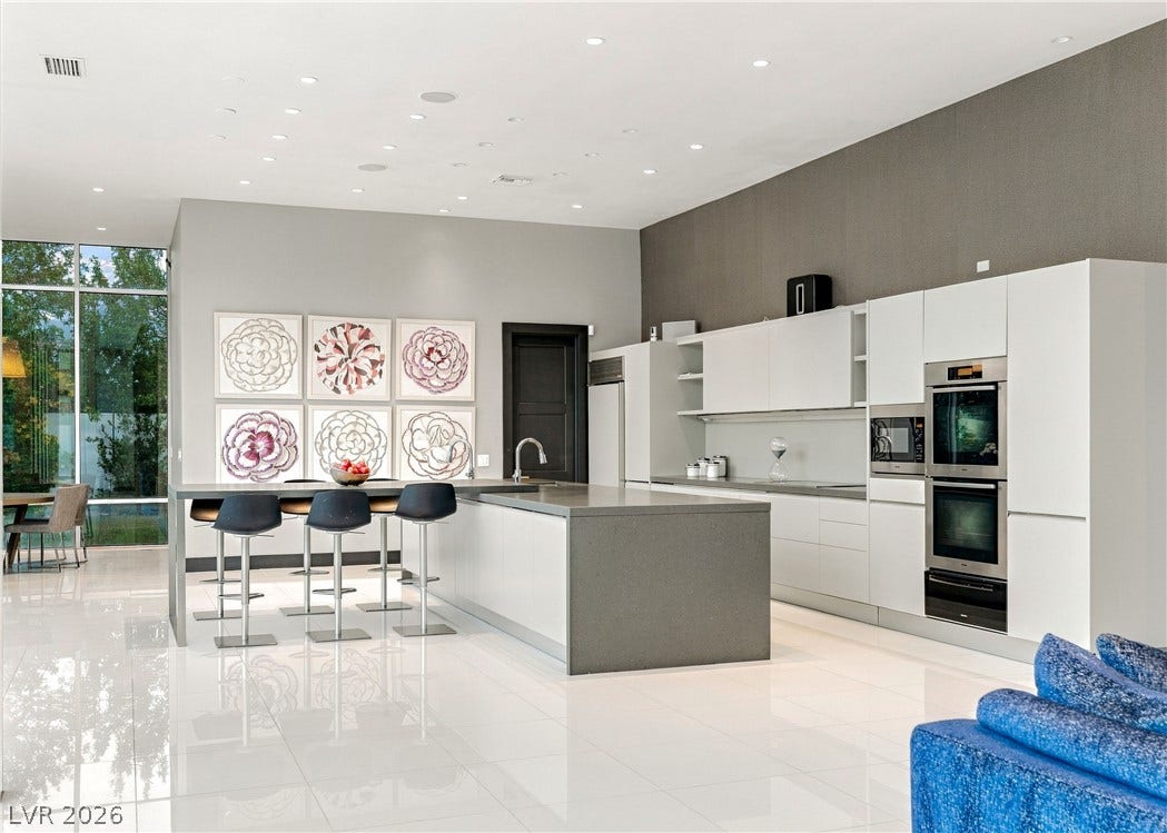 3716 Caesars Circle, Las Vegas, NV 89120 Polished tile flooring and recessed lighting elevate this modern kitchen with a waterfall island.