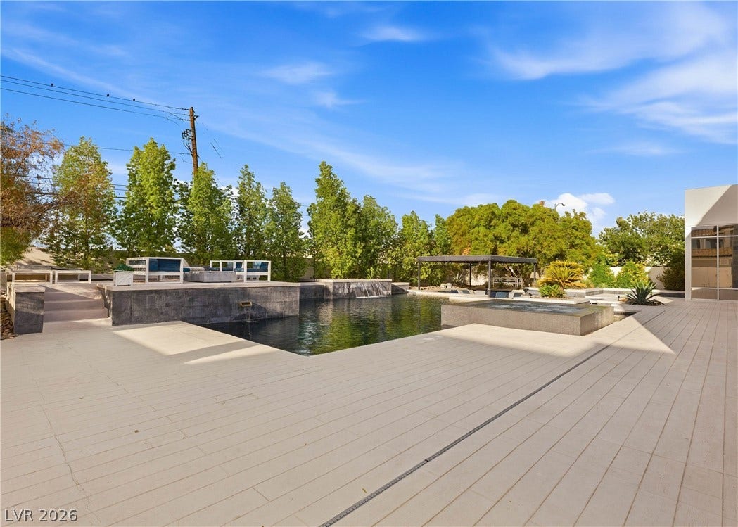 3716 Caesars Circle, Las Vegas, NV 89120 A spacious stone terrace wraps around a modern swimming pool bordered by mature trees.