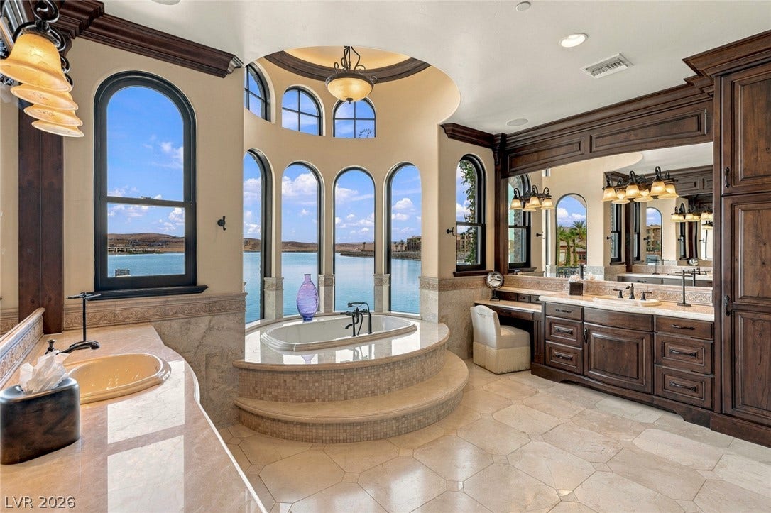 7 Lido Nord, Henderson, NV 89011 Arched windows frame water views from this primary bathroom featuring a stepped soaking tub.