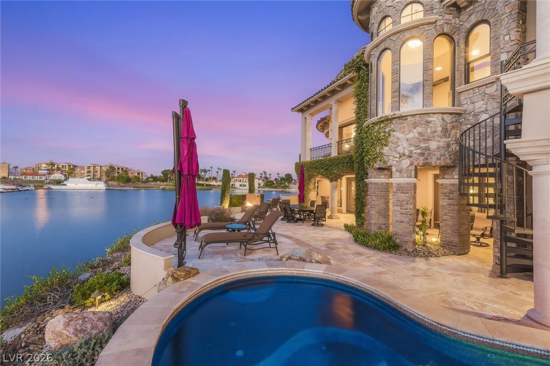 7 Lido Nord, Henderson, NV 89011 A spacious stone patio overlooks the tranquil water at dusk.