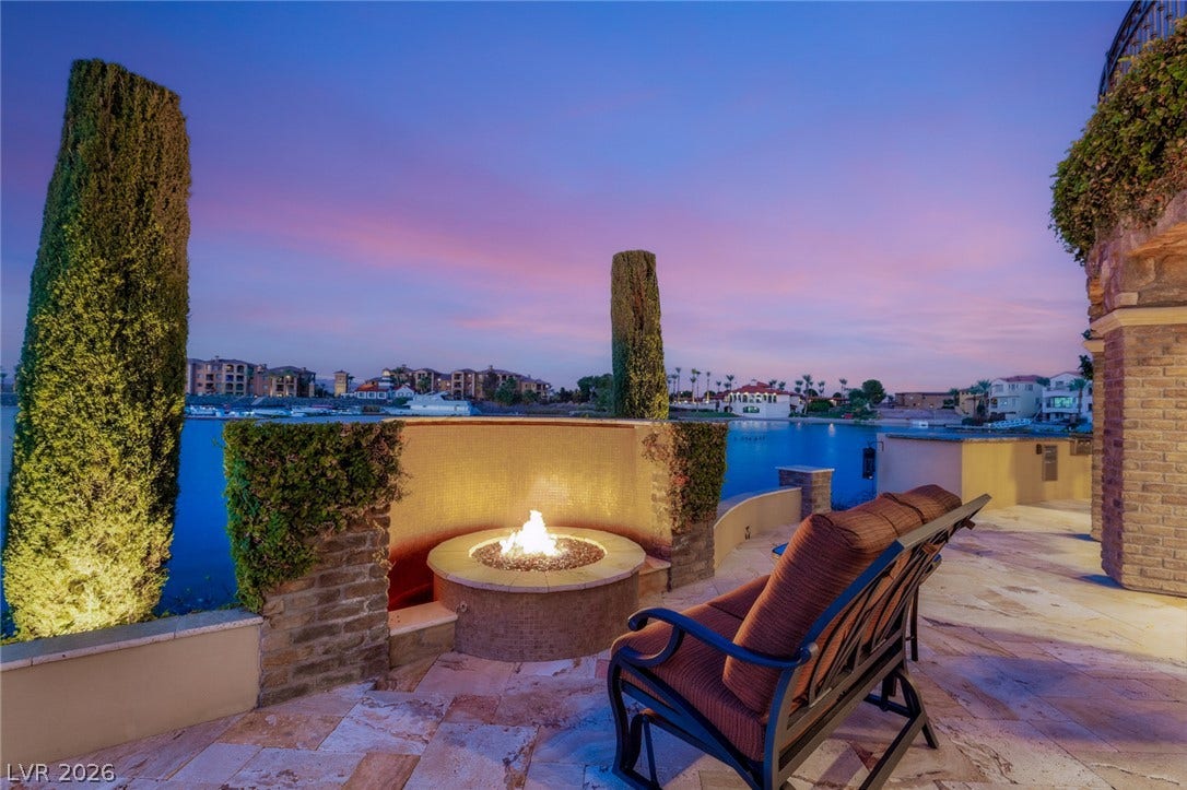 7 Lido Nord, Henderson, NV 89011 An inviting stone patio with a built-in fire pit overlooks serene lakefront waters.