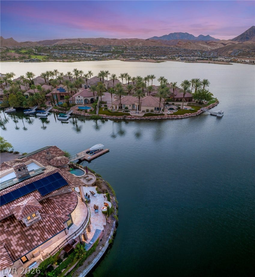 7 Lido Nord, Henderson, NV 89011 Unobstructed lakefront vistas unfold under twilight skies against a backdrop of desert mountains.