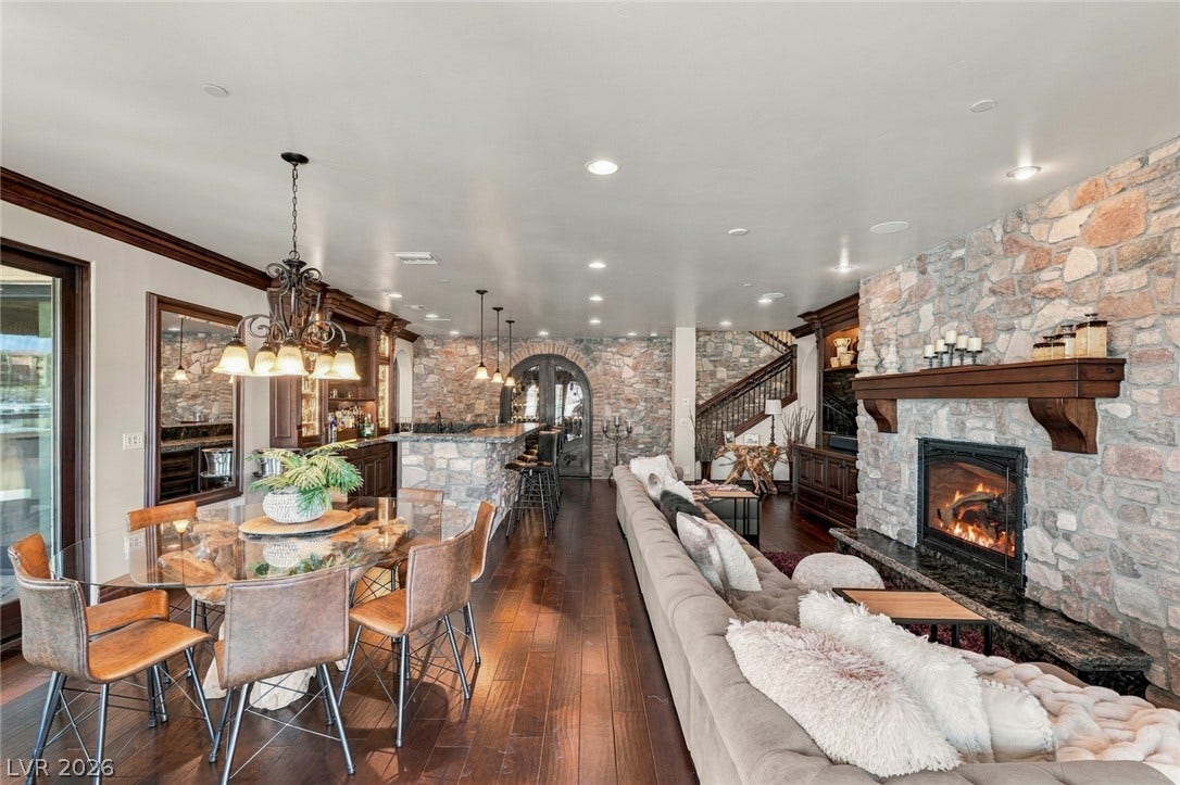7 Lido Nord, Henderson, NV 89011 Rich hardwood floors lead past a stone fireplace and bar in this open living space.