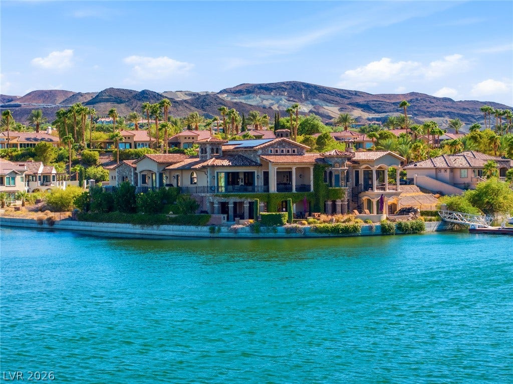 7 Lido Nord, Henderson, NV 89011 A magnificent waterfront estate rises above tranquil blue waters against a dramatic mountain backdrop.