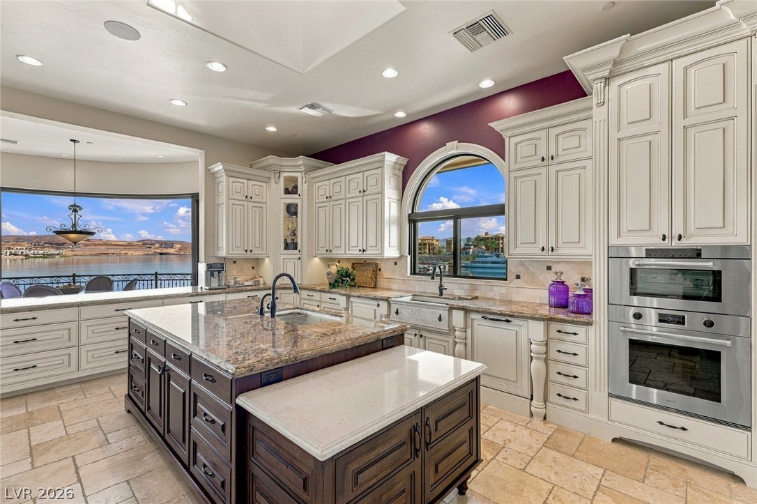 7 Lido Nord, Henderson, NV 89011 Richly detailed cabinetry and stone countertops frame peaceful water views in this chef's kitchen.