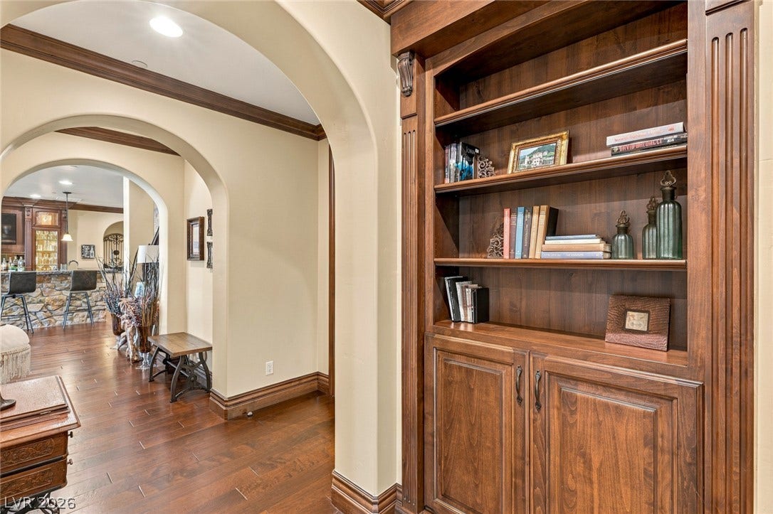7 Lido Nord, Henderson, NV 89011 Rich wood built-ins and arched walkways frame a warm, inviting hallway with hardwood flooring.