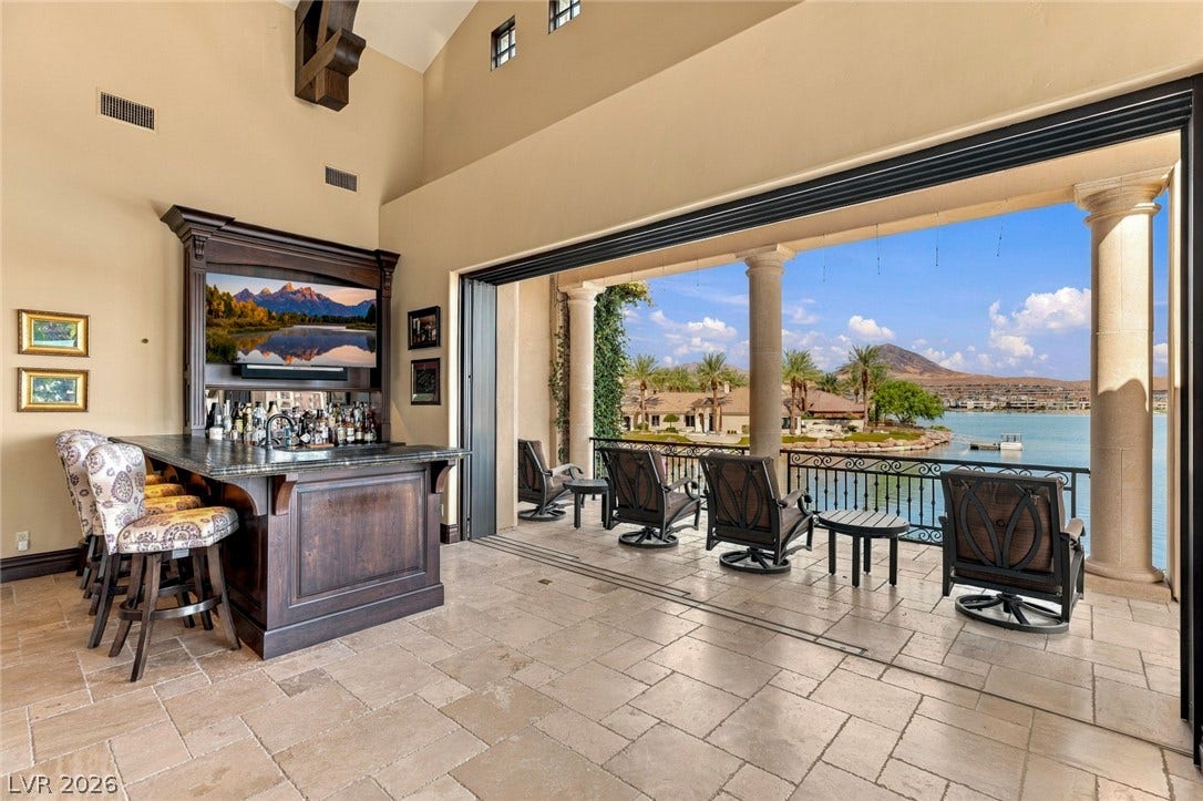 7 Lido Nord, Henderson, NV 89011 Massive sliding glass doors open to reveal sweeping water views past the stone-tiled bar area.