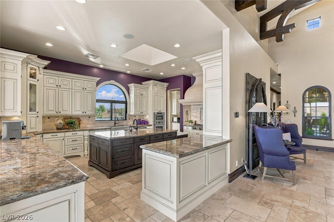 7 Lido Nord, Henderson, NV 89011 Granite countertops, stone tile flooring, and custom cabinetry anchor this open-concept kitchen.