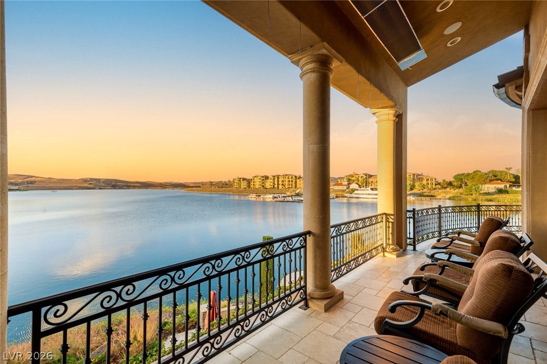 7 Lido Nord, Henderson, NV 89011 An elevated stone patio offers sweeping water views framed by classic architectural columns and wrought-iron railings.