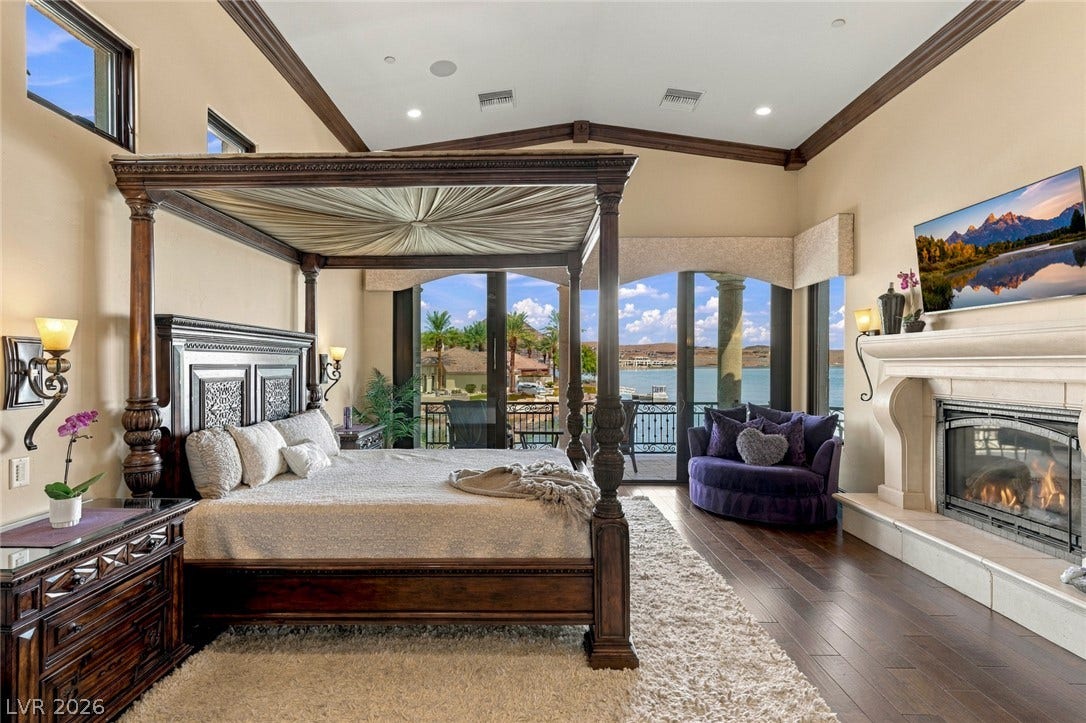 7 Lido Nord, Henderson, NV 89011 Rich hardwood floors and a grand stone fireplace define this expansive primary suite with lakefront views.