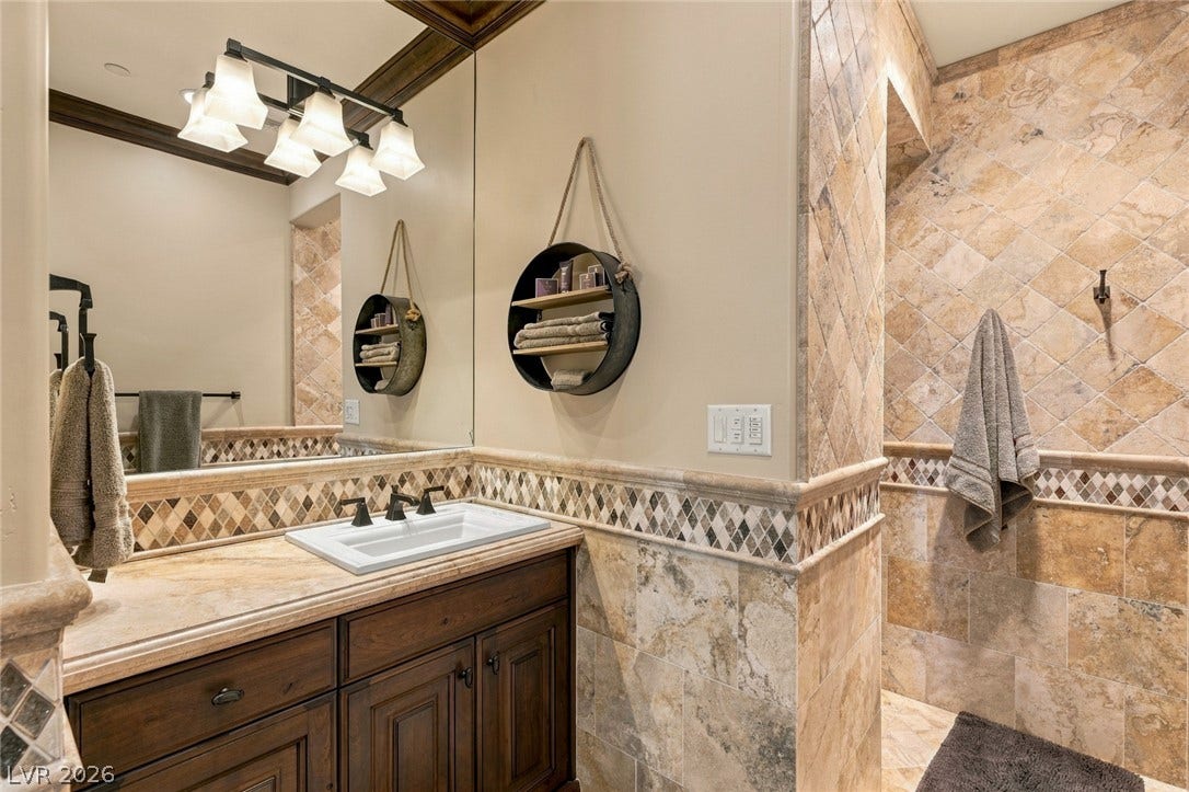 7 Lido Nord, Henderson, NV 89011 Richly textured stone tile and warm wood cabinetry define this elegant bathroom space.