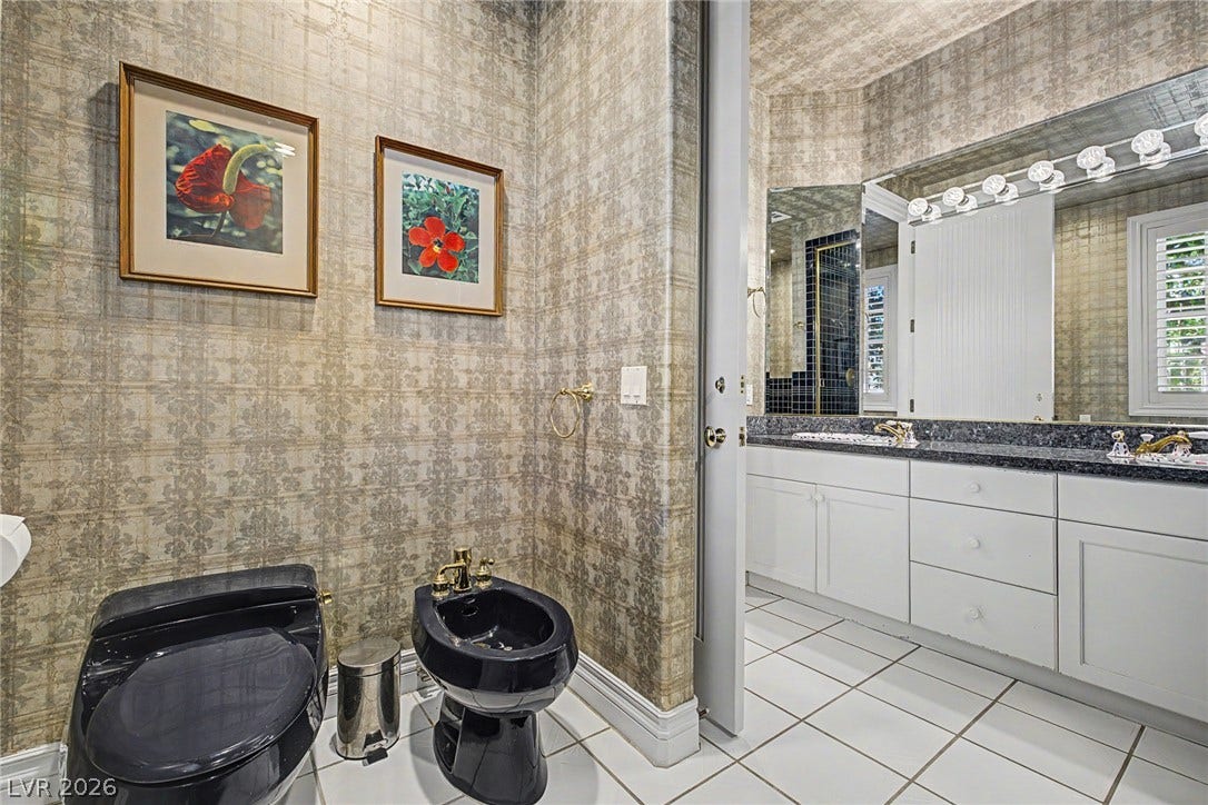1105 Broadmoor Avenue, Las Vegas, NV 89109 Patterned wallpaper and classic tiling frame this master bathroom suite with a dual-vanity setup.
