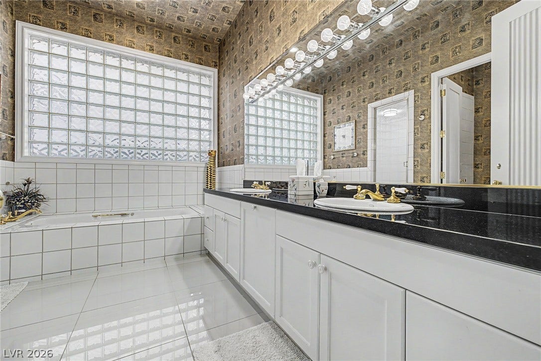 1105 Broadmoor Avenue, Las Vegas, NV 89109 Ornate wallpaper and clean tile define this spacious bathroom equipped with a double vanity.