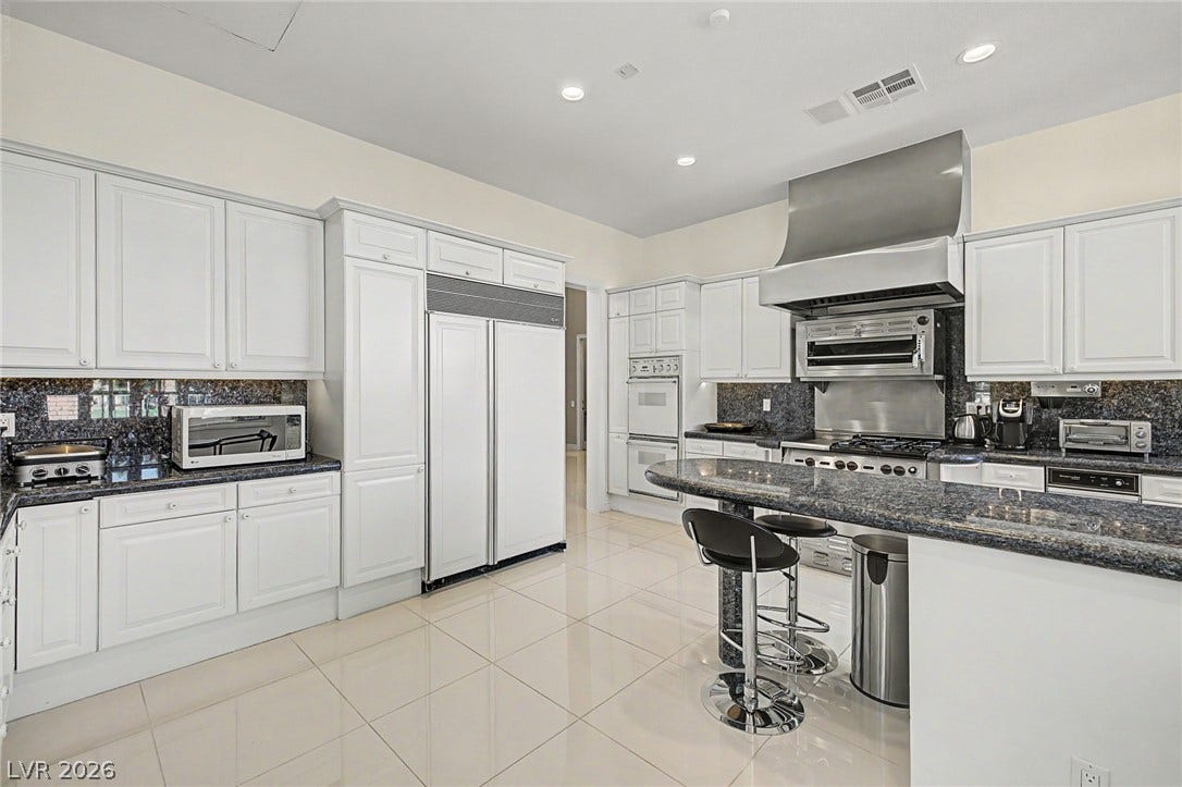 1105 Broadmoor Avenue, Las Vegas, NV 89109 Gleaming tile floors and dark granite countertops define this modern kitchen workspace.
