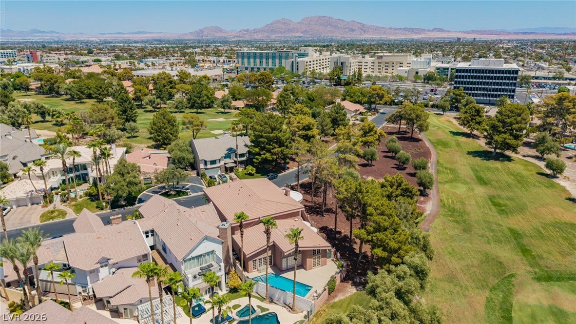 1105 Broadmoor Avenue, Las Vegas, NV 89109 An aerial perspective showcases a backyard pool bordering a golf course against a mountain backdrop.