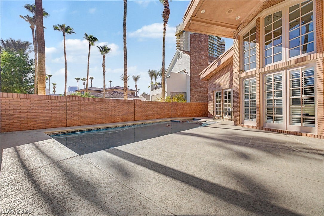 1105 Broadmoor Avenue, Las Vegas, NV 89109 Towering palm trees frame an inviting in-ground pool bordered by a classic brick privacy wall.