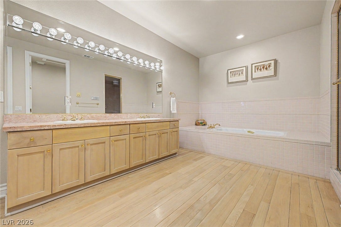 1105 Broadmoor Avenue, Las Vegas, NV 89109 A spacious bathroom features wood floors, a built-in soaking tub, and an expansive double vanity.