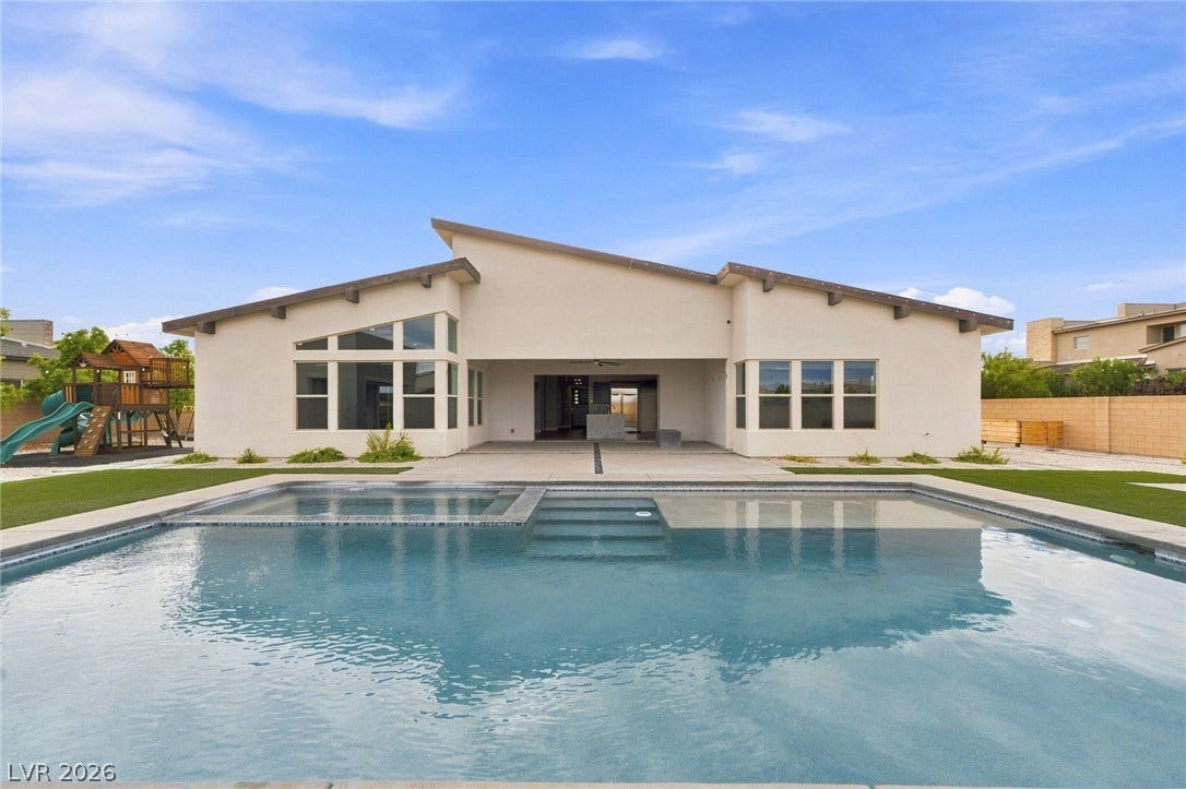 8380 Mojave Creek Court, Las Vegas, NV 89113 An inviting backyard setting features a sparkling swimming pool under clear blue skies.