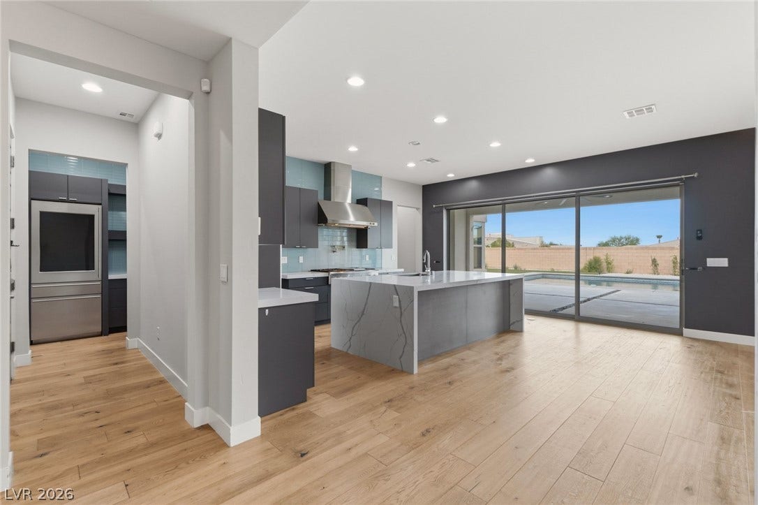 8380 Mojave Creek Court, Las Vegas, NV 89113 Gleaming wood floors anchor a modern, open-concept kitchen opening to a poolside patio.