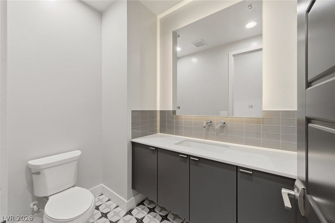 8380 Mojave Creek Court, Las Vegas, NV 89113 Geometric patterned tile floors and wall-mounted faucets define this modern vanity area.