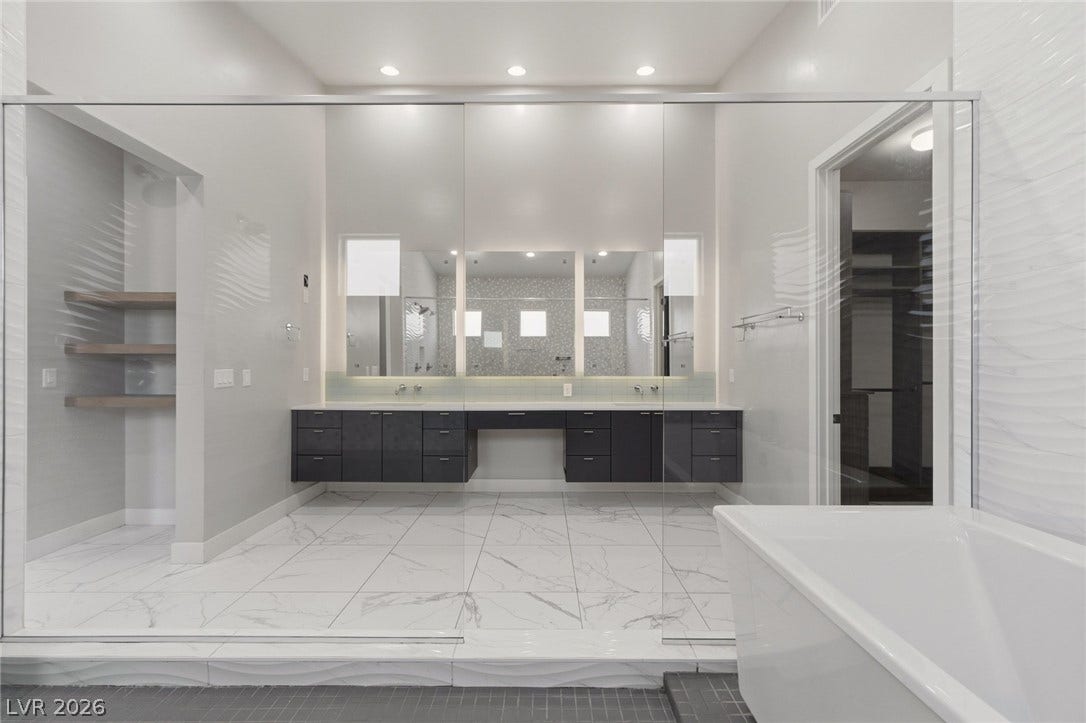 8380 Mojave Creek Court, Las Vegas, NV 89113 Gleaming marble-patterned tile floors and an expansive vanity anchor this modern primary bath.