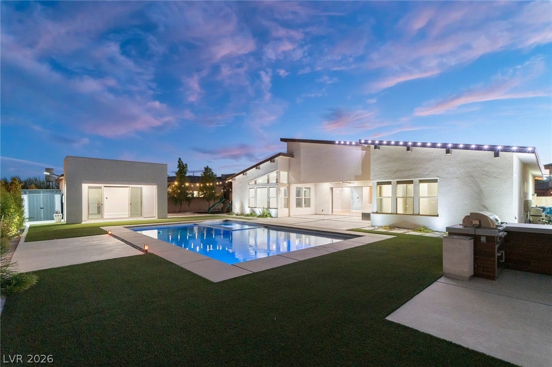 8380 Mojave Creek Court, Las Vegas, NV 89113 An inviting backyard oasis centers around a sparkling swimming pool under an evening sky.