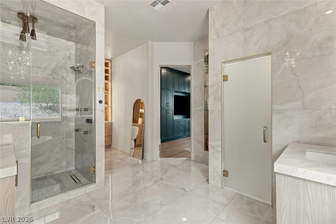40 Stonemark Drive, Henderson, NV 89052 Polished tile flooring and walls elevate this sophisticated bathroom featuring a glass walk-in shower.
