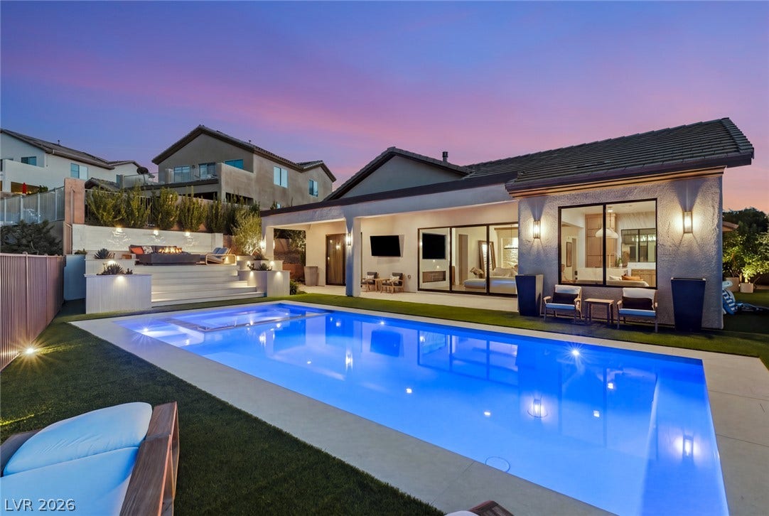 40 Stonemark Drive, Henderson, NV 89052 An inviting backyard oasis features a glowing swimming pool, tiered patio spaces, and modern architecture.