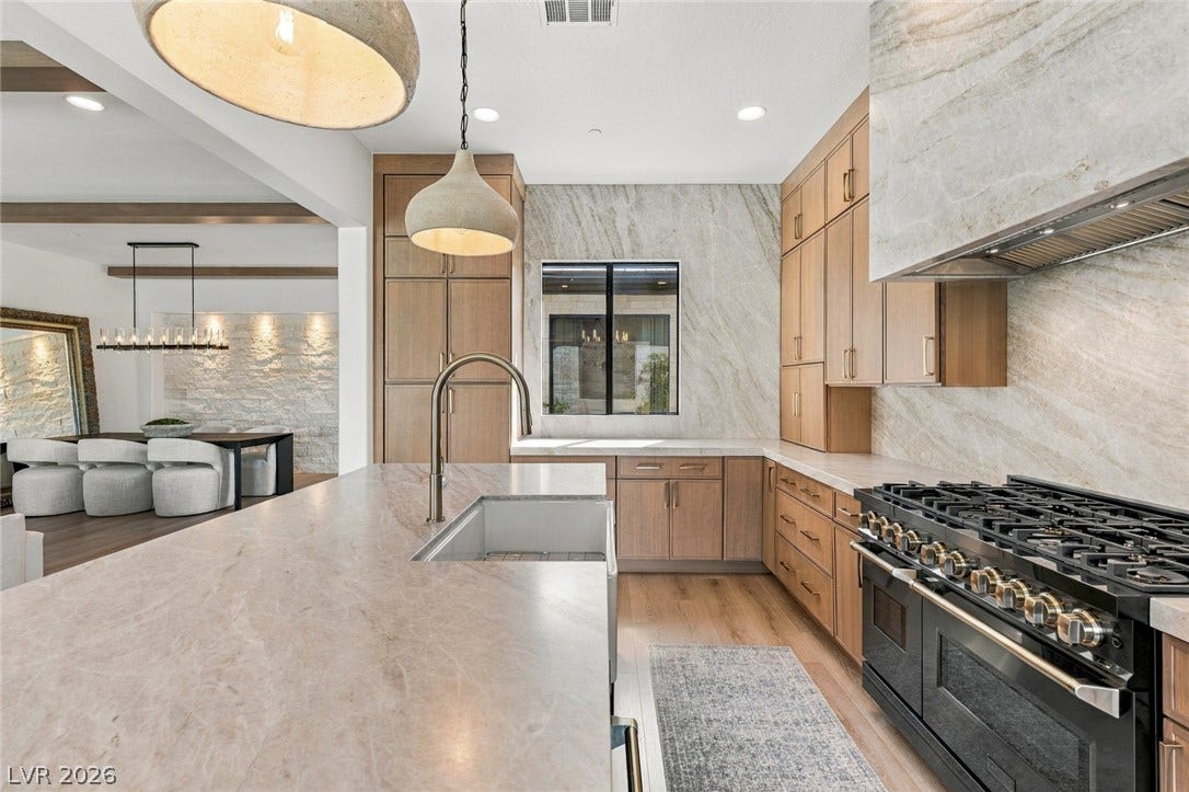 40 Stonemark Drive, Henderson, NV 89052 Fine stonework and wood cabinetry frame a high-end culinary space featuring a large central island.