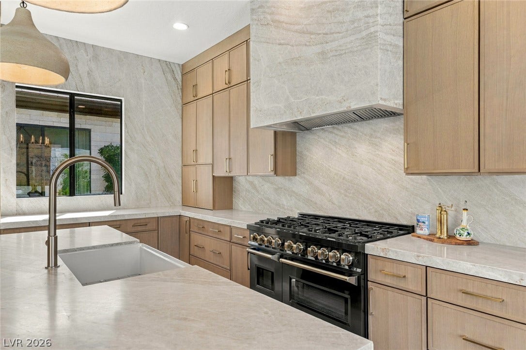 40 Stonemark Drive, Henderson, NV 89052 Richly grained stone backsplashes and custom cabinetry define this thoughtfully crafted culinary space.