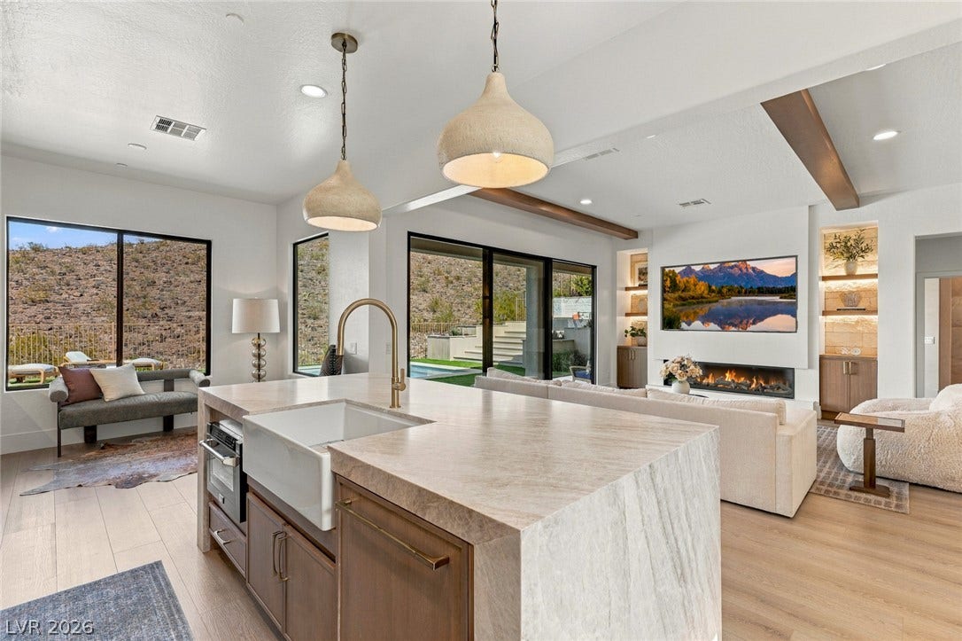 40 Stonemark Drive, Henderson, NV 89052 Gleaming stone countertops and wood flooring flow seamlessly into an inviting fireplace-lit living room.