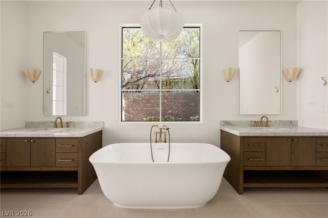 12007 Oakland Hills Drive, Las Vegas, NV 89141 An elegant soaking tub sits between dual vanities below a large picture window.