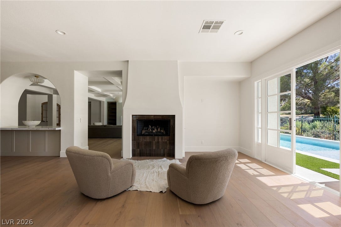 12007 Oakland Hills Drive, Las Vegas, NV 89141 Hardwood floors and a central fireplace anchor this inviting living space overlooking the pool.