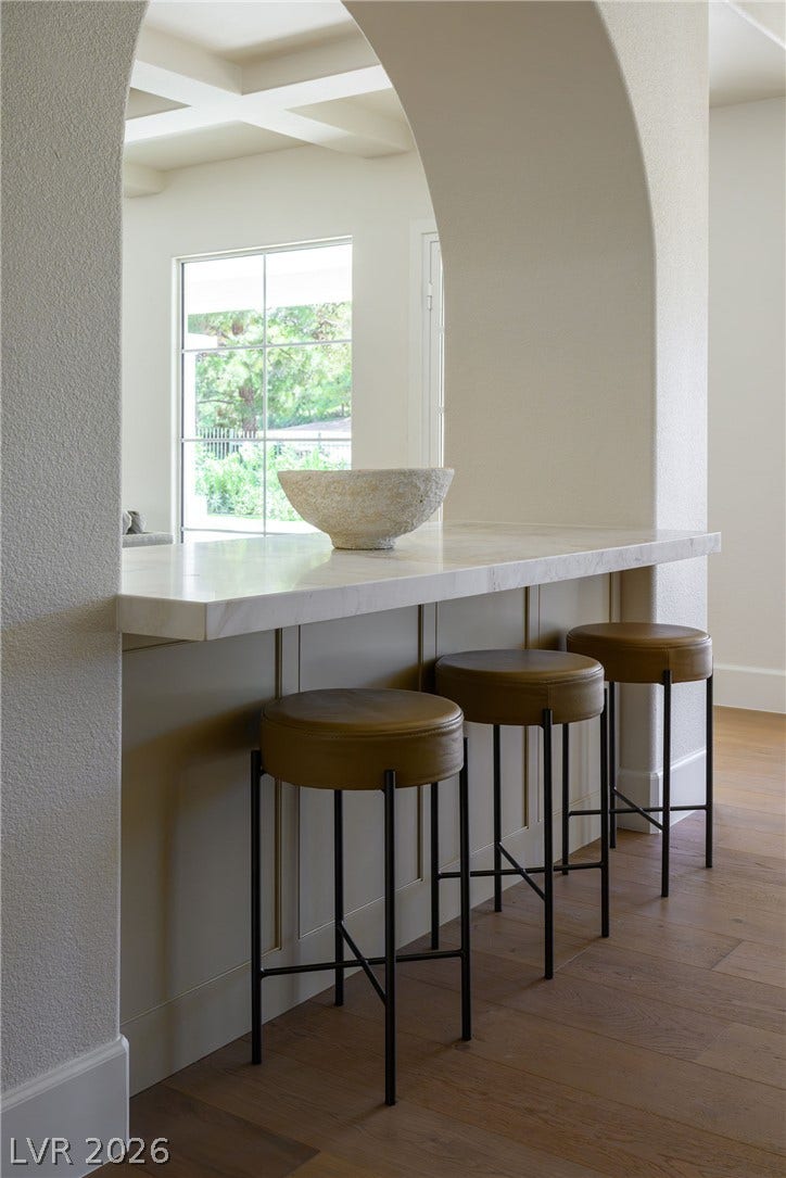 12007 Oakland Hills Drive, Las Vegas, NV 89141 A graceful arched opening frames a stone breakfast bar set over warm wood floors.